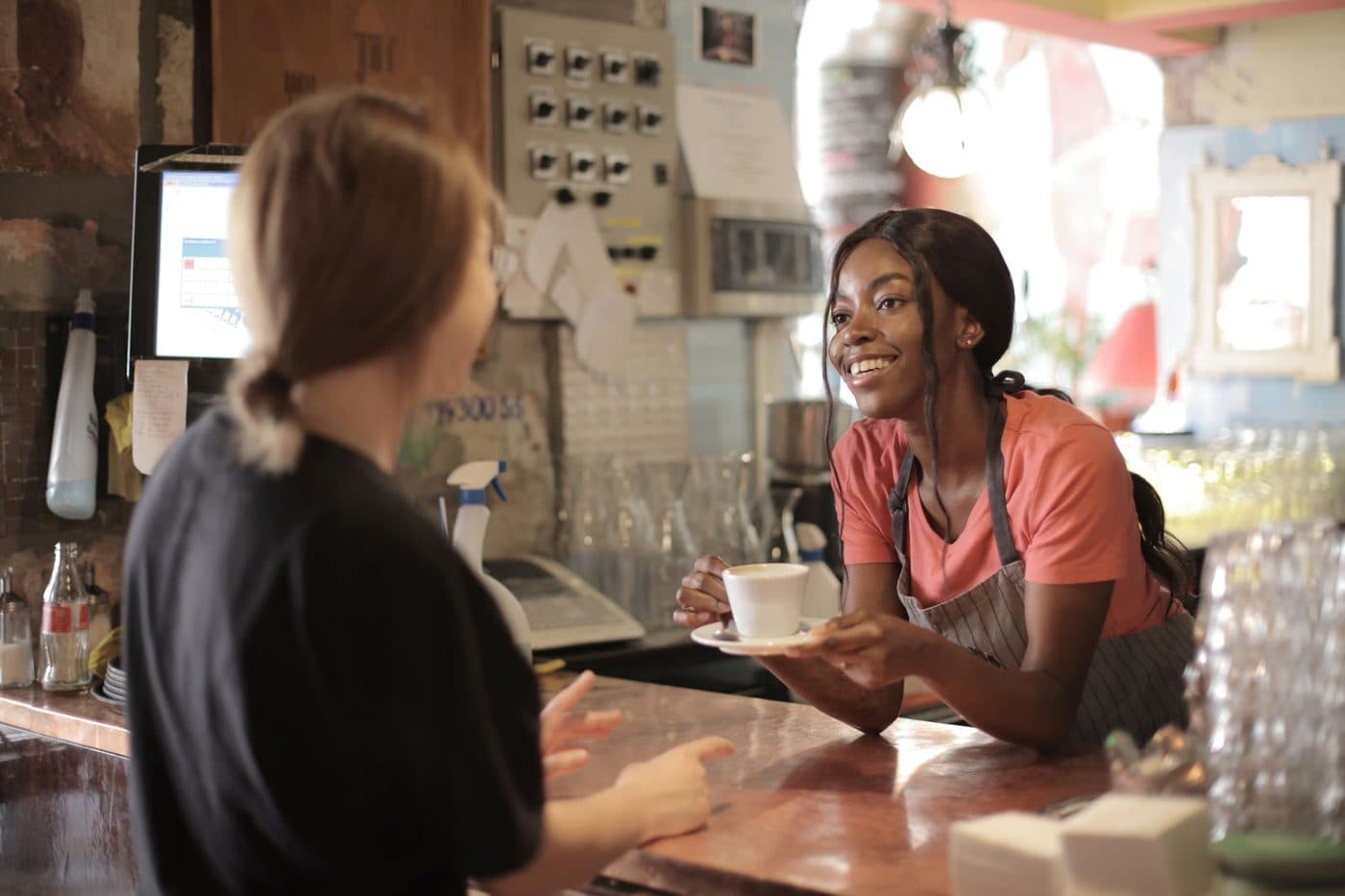 A barista handing a coffee to a customer across the counter