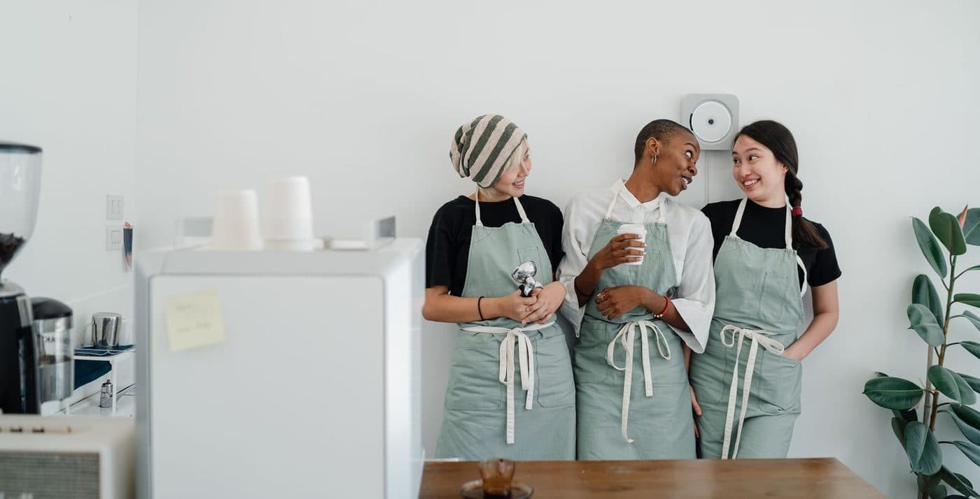 Three team members in aprons talking during a shift